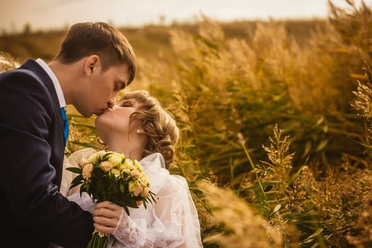 young bride and groom on the background of the field