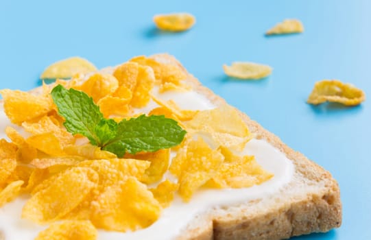 Cornflakes on Yogurt on Bread with Peppermint on Blue Pastel Background Left. Cereal Breakfast bread healthy clean food for food and dessert category