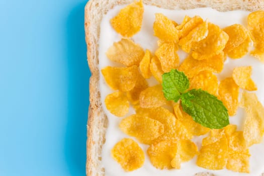 Cornflakes on Yogurt on Bread with Peppermint on Blue Pastel Background Flatlay Close Up. Cereal Breakfast bread healthy clean food for food and dessert category