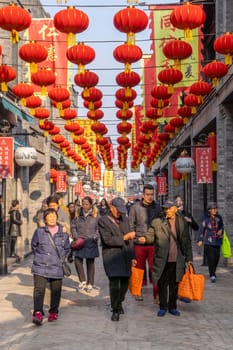 Beijing, China - Mar 18, 2018: Chinese walking an alley in Qianmen Shopping Street in Beijing. It is the oldest shopping street in Beijing.