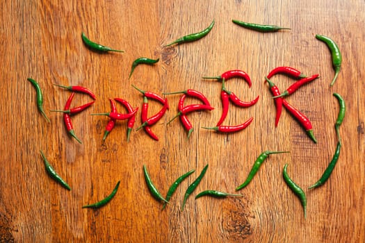 word from chili peppers on a wooden background