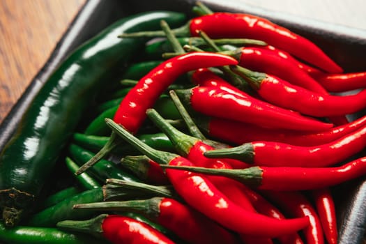 red and green chili peppers close up on wooden background