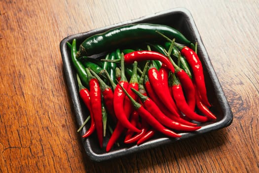red and green chili peppers close up on wooden background