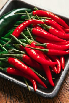 red and green chili peppers close up on wooden background