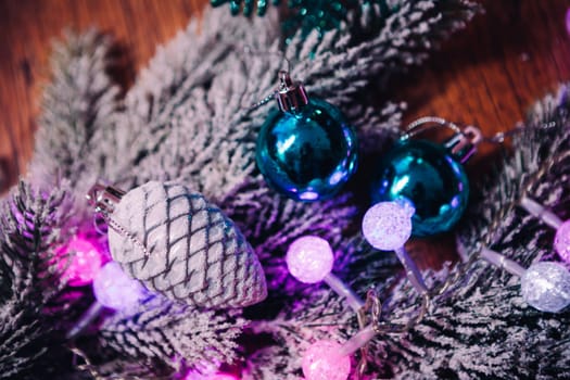 Spruce branches in the snow violet blue and white christmas balls on dark wooden background
