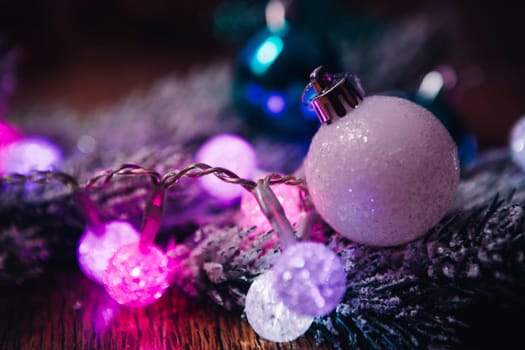 Spruce branches in the snow violet blue and white christmas balls on dark wooden background