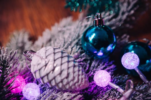 Spruce branches in the snow violet blue and white christmas balls on dark wooden background