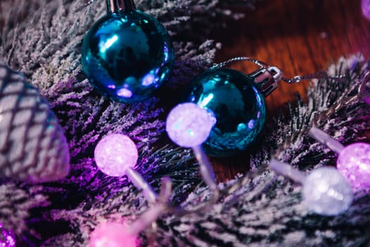 Spruce branches in the snow violet blue and white christmas balls on dark wooden background