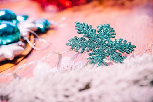 Spruce branches in the snow, and blue snowflake wooden background