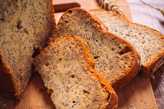 Close slice of fresh bread with poppy seeds on a wooden background