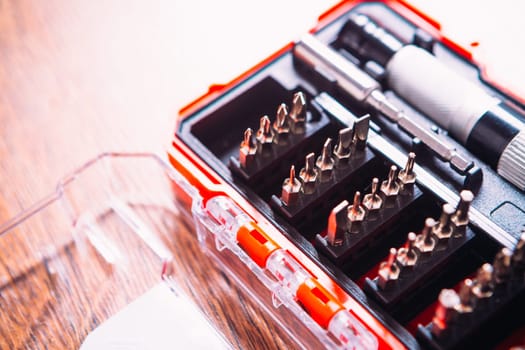 set of nozzles for screwdriver in red box on wooden background