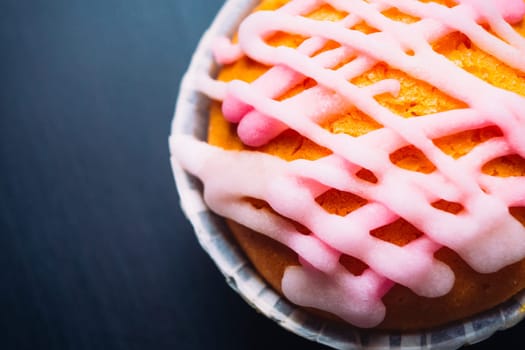 cupcake with pink frosting on a wooden background