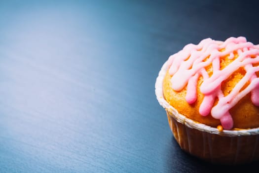 cupcake with pink frosting on a wooden background