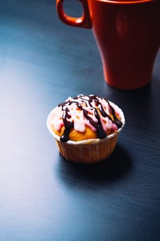 cupcake with pink frosting and red cup on a wooden background