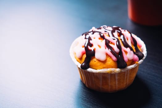 cupcake with pink frosting and red cup on a wooden background