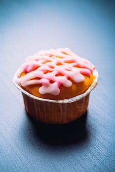 cupcake with pink frosting on a wooden background