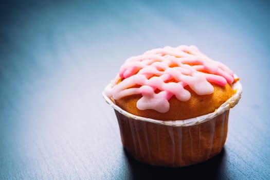 cupcake with pink frosting on a wooden background