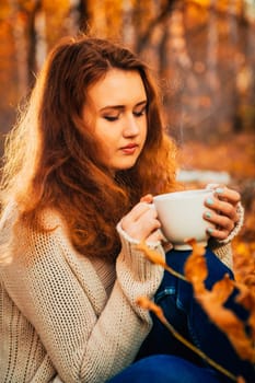 girl with a cup of tea on a background of autumn forest