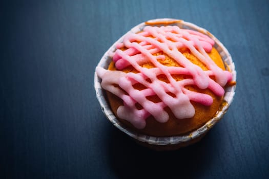 cupcake with pink frosting on a wooden background