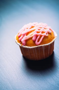 cupcake with pink frosting on a wooden background