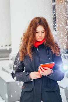 girl stands on the background of the building columns and looking at tablet