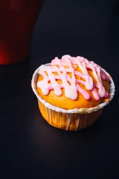 cupcake with pink frosting and red cup on a wooden background