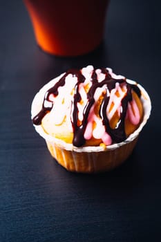 cupcake with pink frosting and red cup on a wooden background