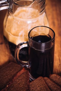 Russian brew in mug jug and loaf of rye flour on wooden background