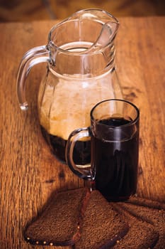 Russian brew in mug jug and loaf of rye flour on wooden background