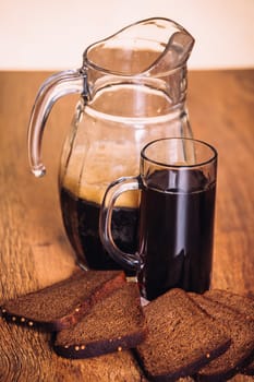 Russian brew in mug jug and loaf of rye flour on wooden background