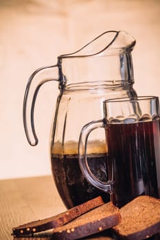 Russian brew in mug jug and loaf of rye flour on wooden background