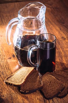 Russian brew in mug jug and loaf of rye flour on wooden background
