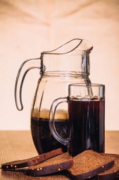 Russian brew in mug jug and loaf of rye flour on wooden background