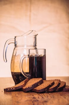 Russian brew in mug jug and loaf of rye flour on wooden background