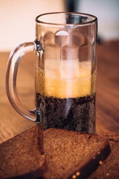 Russian brew in mug and loaf of rye flour on wooden background