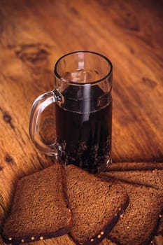 Russian brew in mug and loaf of rye flour on wooden background