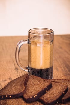 Russian brew in mug and loaf of rye flour on wooden background