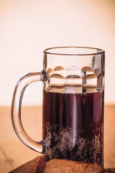 Russian brew in mug and loaf of rye flour on wooden background