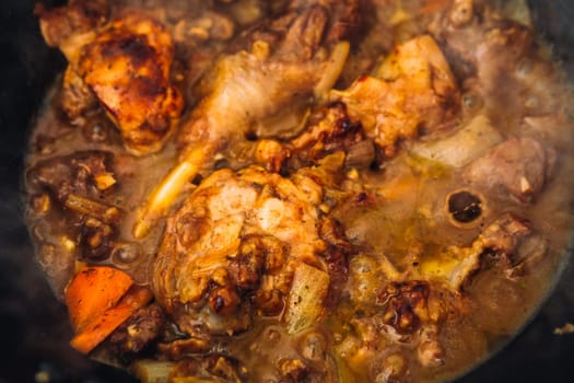 chicken in sauce with carrots in a pan closeup