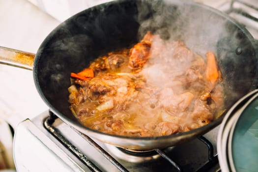 chicken in sauce with carrots in a pan closeup