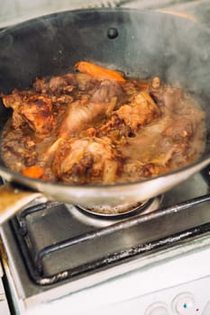chicken in sauce with carrots in a pan closeup