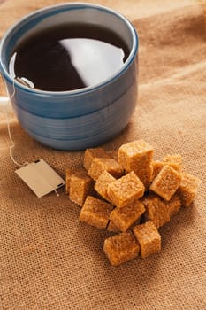 blue cup of tea and lump sugar on sacking background