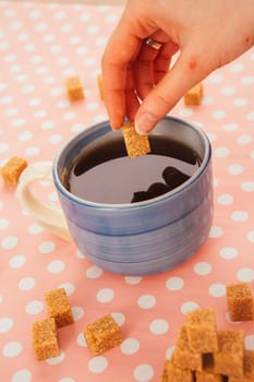 blue cup of tea and lump sugar on pink background