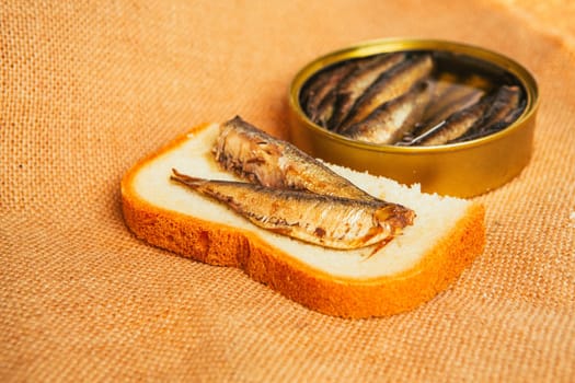 open can and sandwich with of sprats on sackcloth background