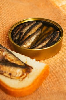 open can and sandwich with of sprats on sackcloth background