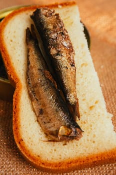 open can and sandwich with of sprats on sackcloth background