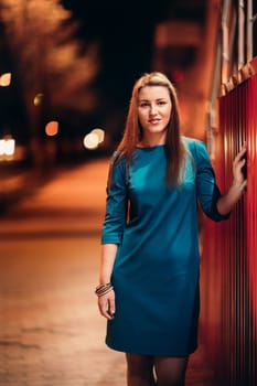 beautiful girl in a blue dress against the backdrop of the city at night