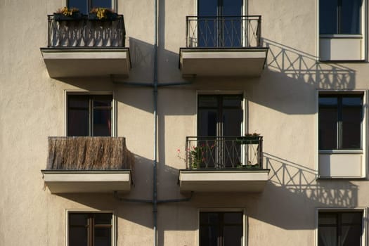 The railings of small nostalgic balconies of an apartment building cast shadows.