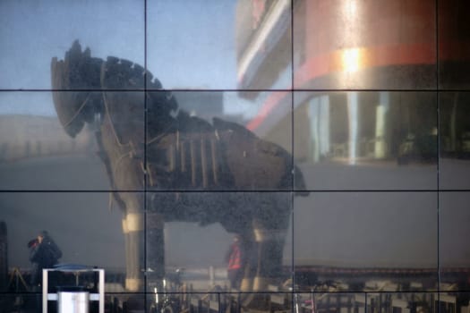Berlin, Germany - November 06, 2018: The wooden sculpture and replica of the Trojan Horse mirrored in shop windows of a department store on November 06, 2018 in Berlin