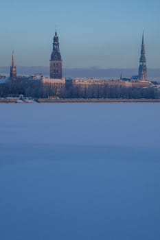 Riga view in winter  Riga, capital city of Latvia in winter time. View of St Peter's Church, St. Jacob's Cathedral and Anglican Church. View of Old Riga with frozen river Daugava in the foreground. City Riga with background of blue sky.